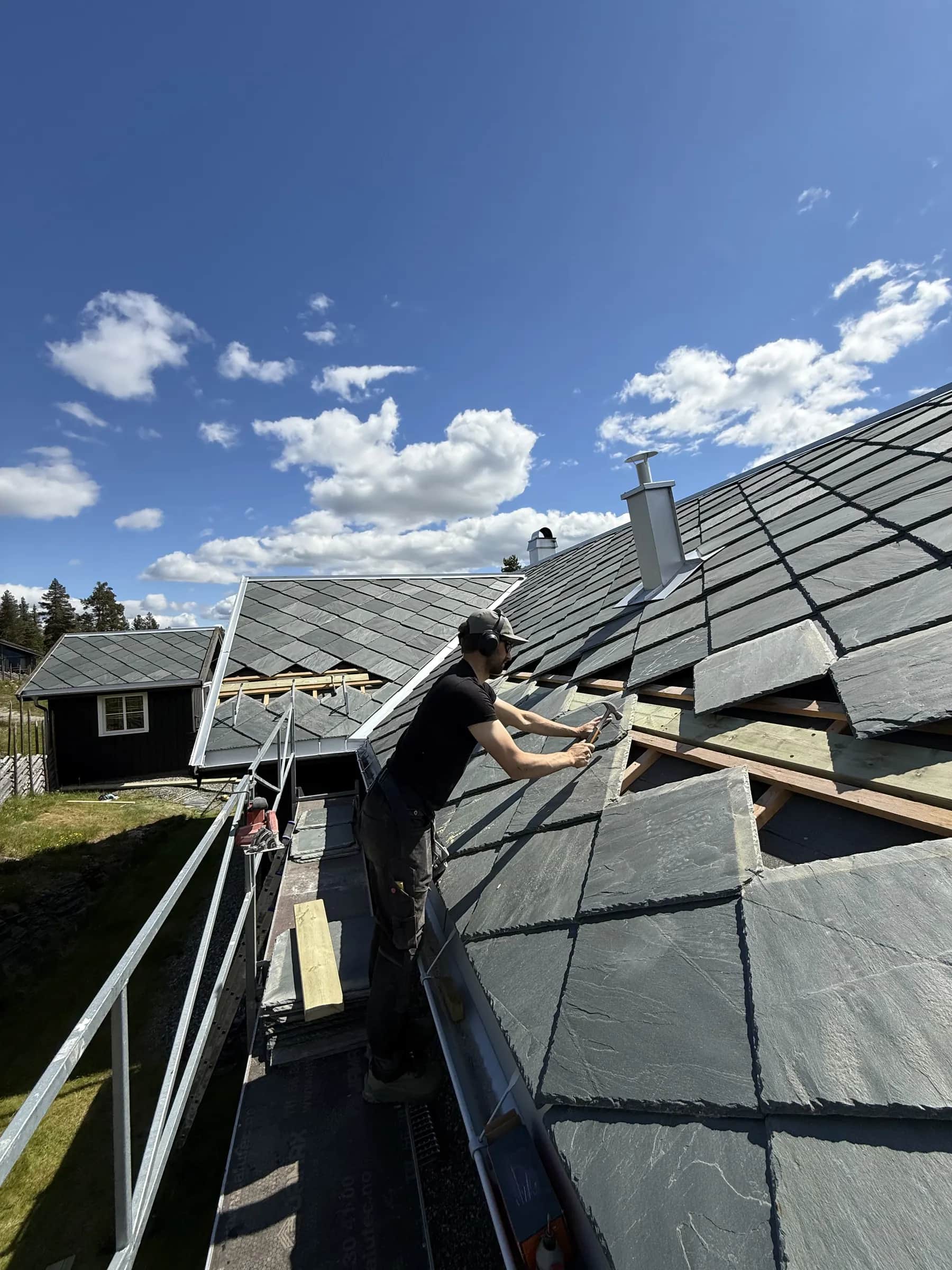 Skiferlegger i arbeid med skifer på lektet tak