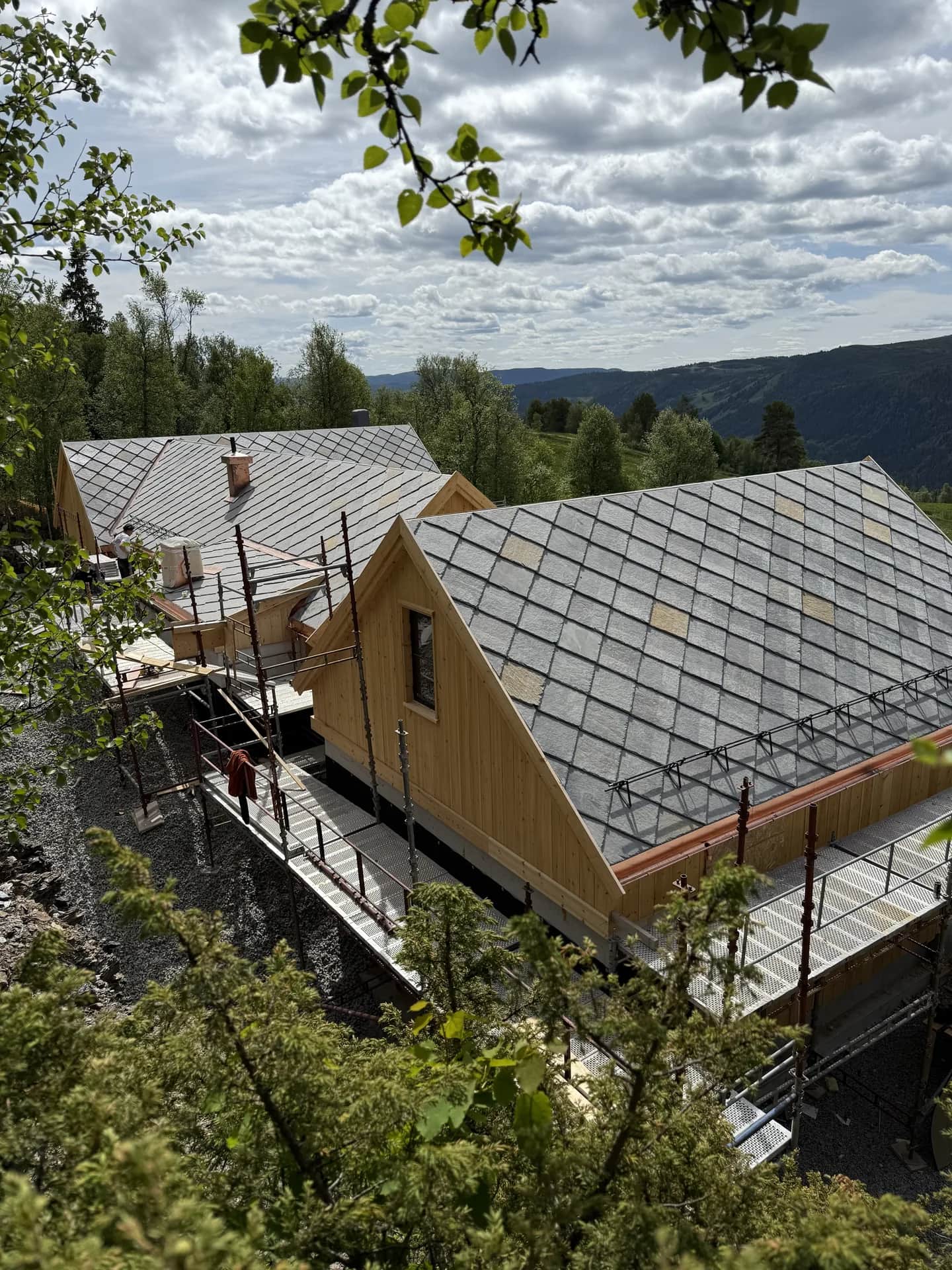 Hytte med skifertak ved fjorden og fjellandskap